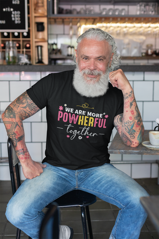 Man sitting in a cafe wearing a black t-shirt with a colorful message.