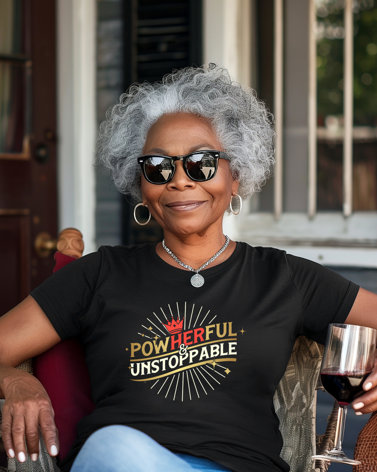 Woman wearing a black t-shirt with motivational text, sitting outdoors with a glass of wine.