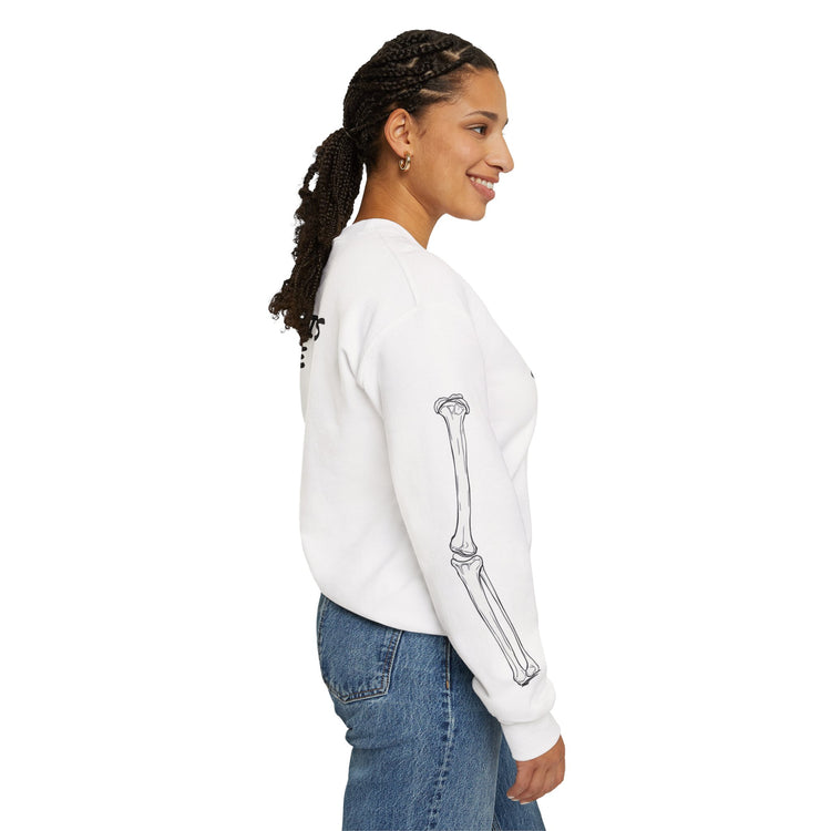 Woman wearing a white sweatshirt with a skeleton design on the sleeve, standing against a white background.
