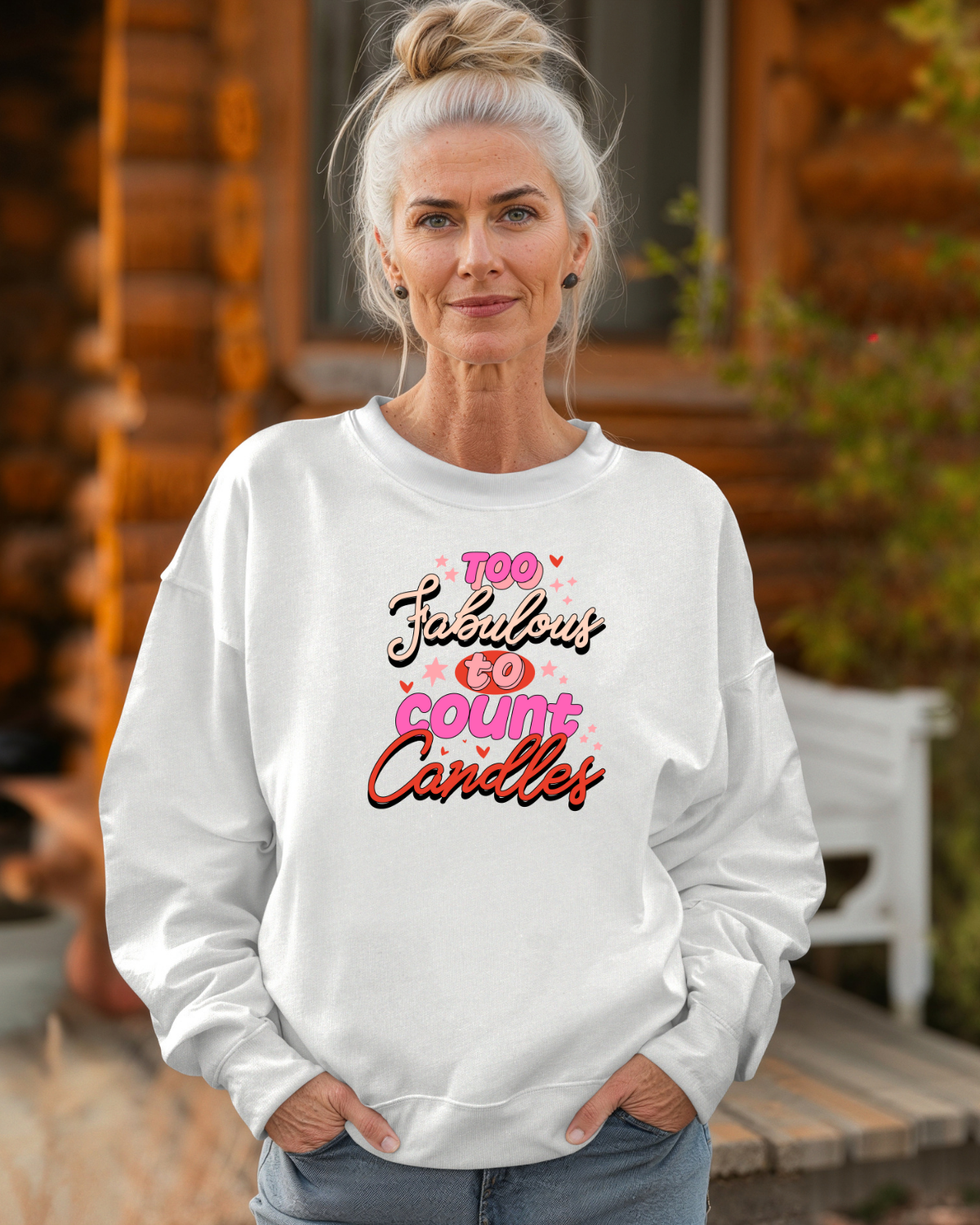 Woman wearing a white sweatshirt with colorful text "Too Fabulous to count candles"